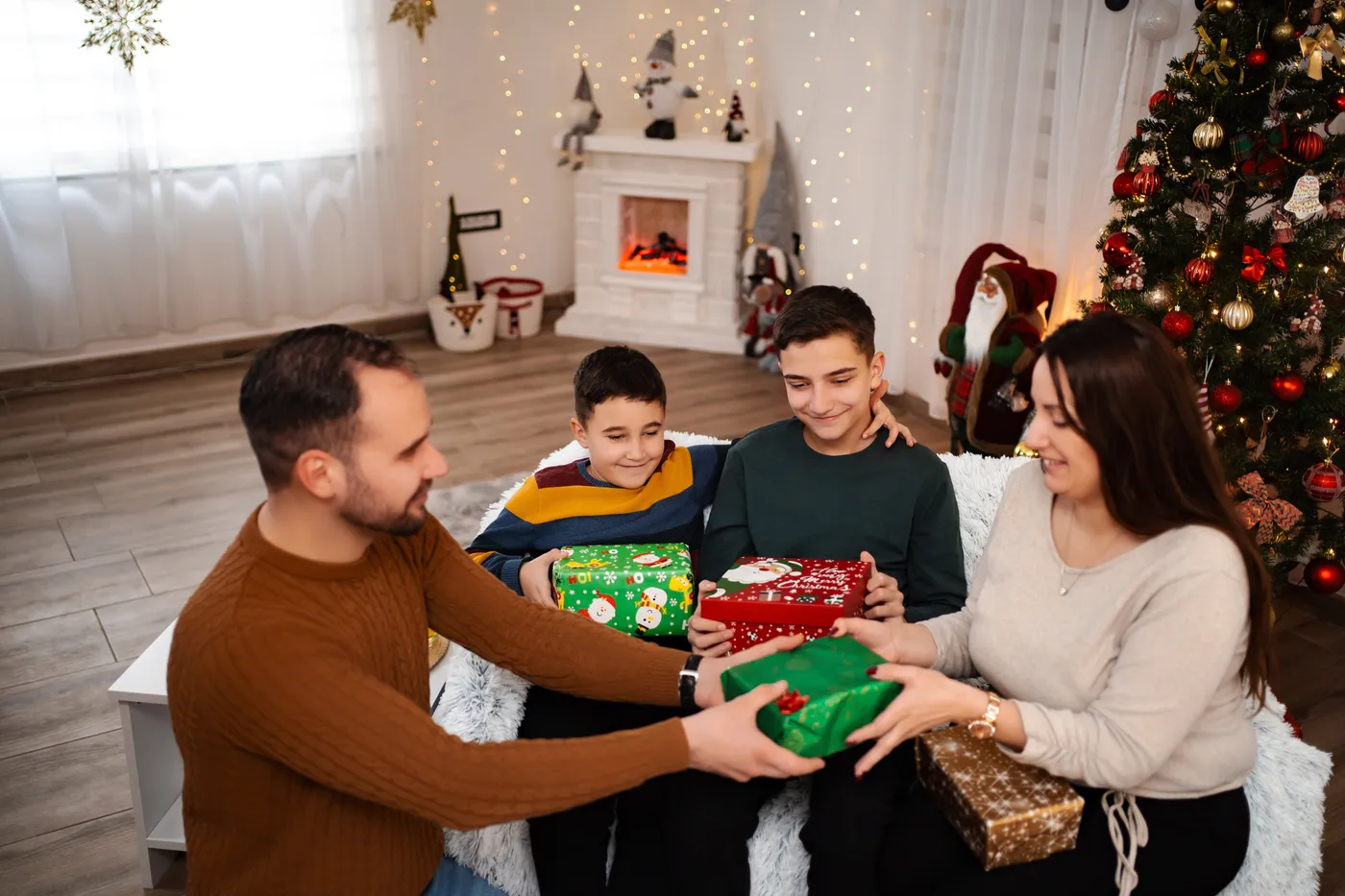 Famille échangeant des cadeaux près du sapin de Noël