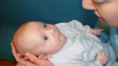 Une maman tient son bébé dans ses bras et lui fait des signes