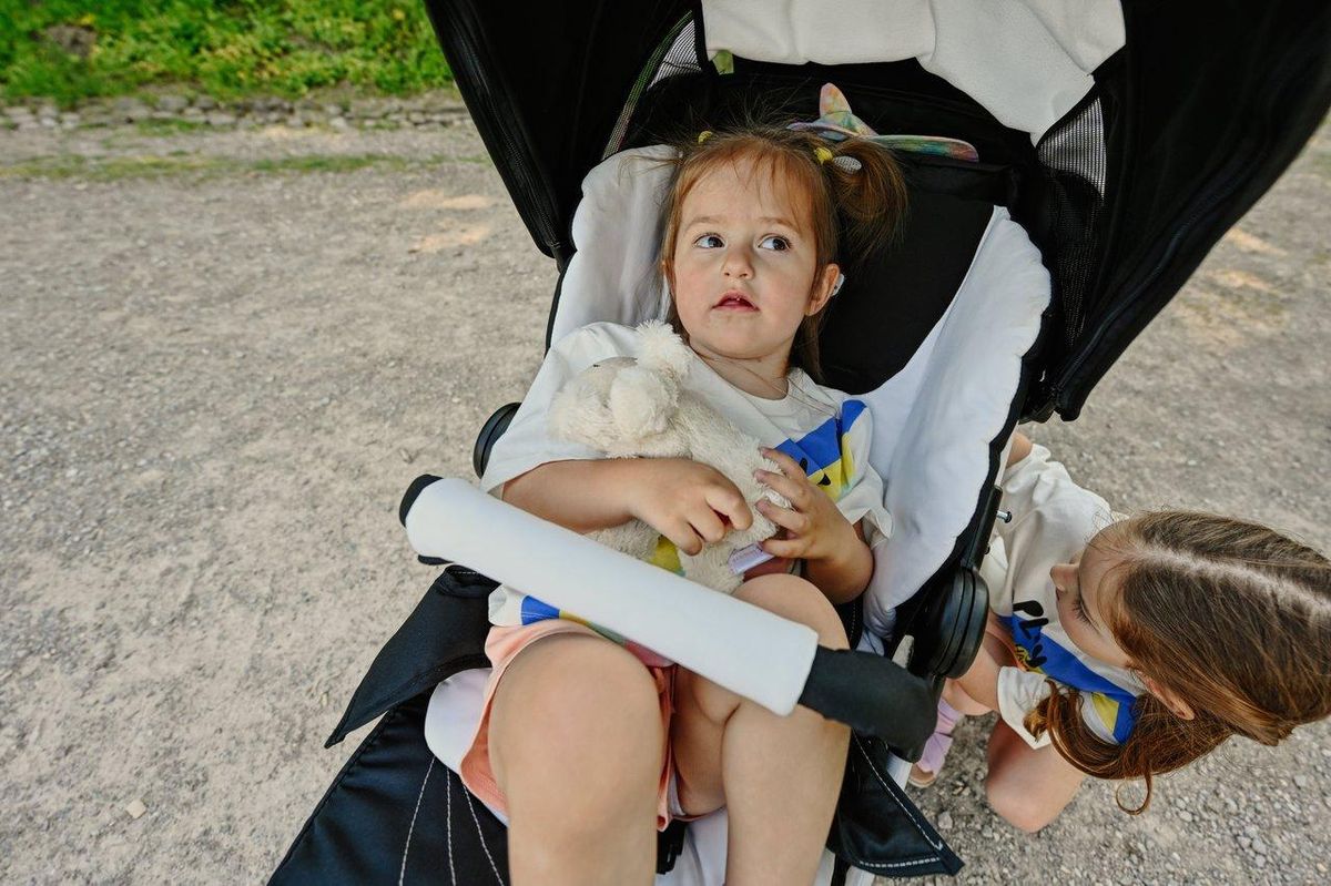 Baby tenant un doudou doux dans une poussette en plein air lors d'une sortie en famille.