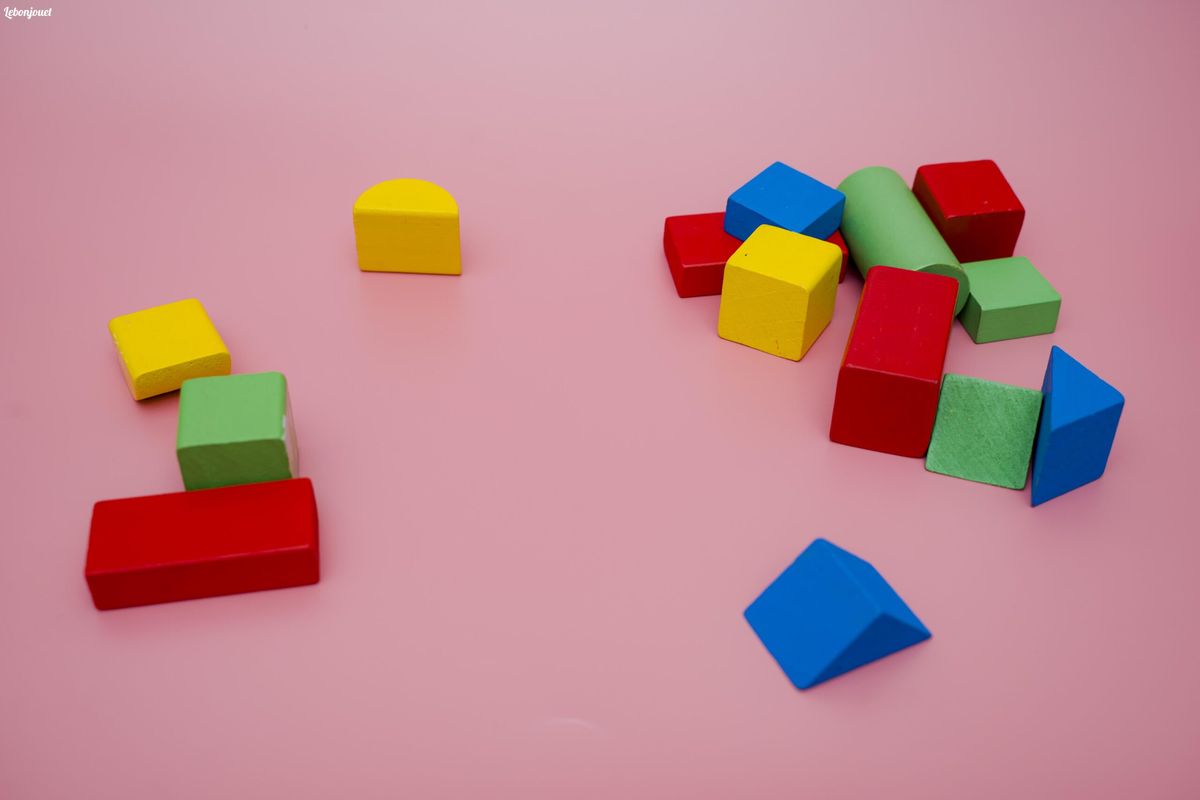 Blocs en bois colorés sur fond rose: éco-responsables, ludiques et durables pour vos enfants.