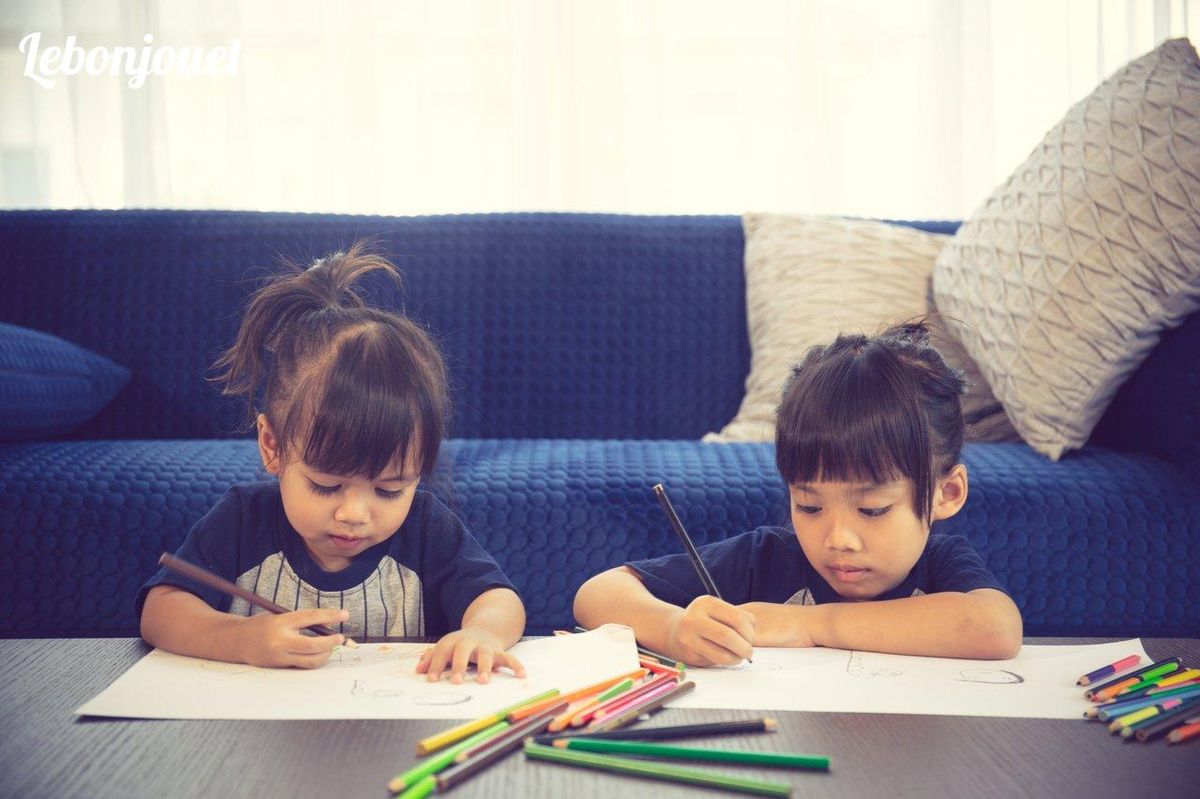 Deux enfants dessinent avec soin, affinant leur motricité fine à chaque trait de crayon.