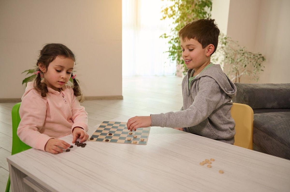 Deux enfants jouant à un jeu de société, illustrant une activité ludique pour enfants de 3 à 6 ans.