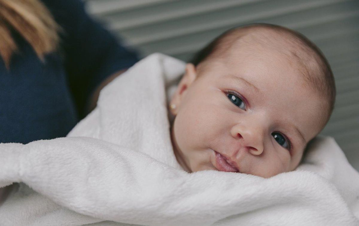 Doudou bio en coton blanc posé sur une couverture douce, idéal pour la peau sensible de bébé.