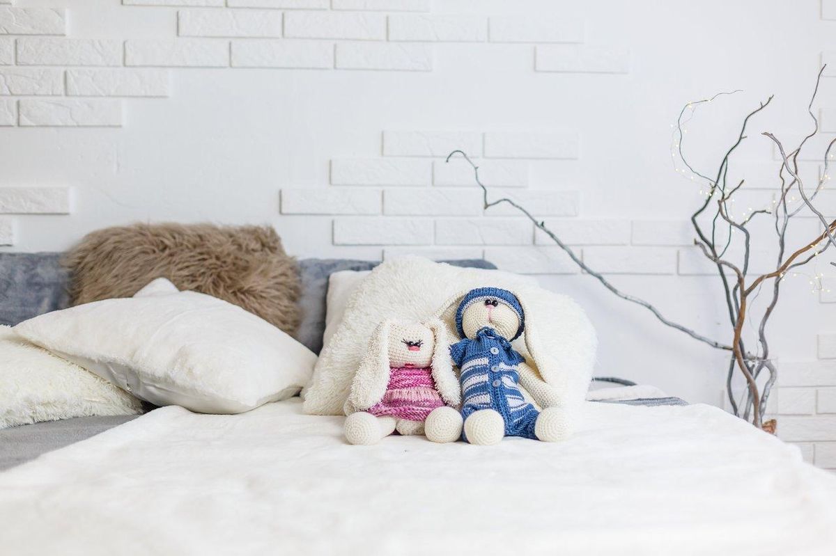 Doudous colorés de différentes couleurs sur un lit d'enfant, illustrant la gestion de plusieurs doudous de secours.
