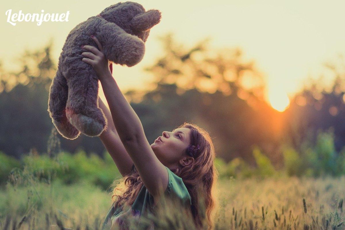 Enfant et peluche au coucher du soleil : dialogue entre nature et technologie.
