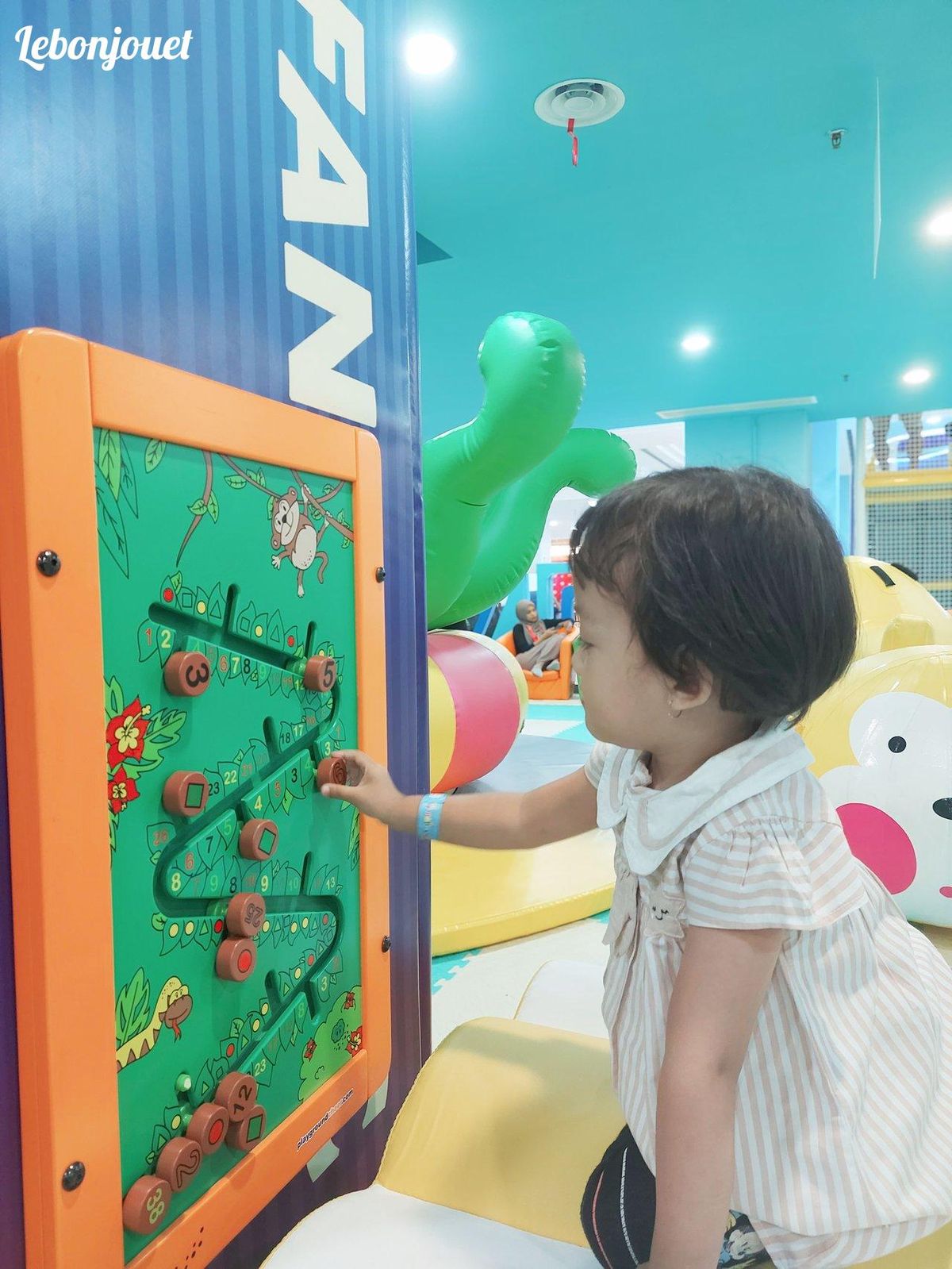 Enfant explorant un panneau ludique, parfait pour développer la motricité fine avec créativité.