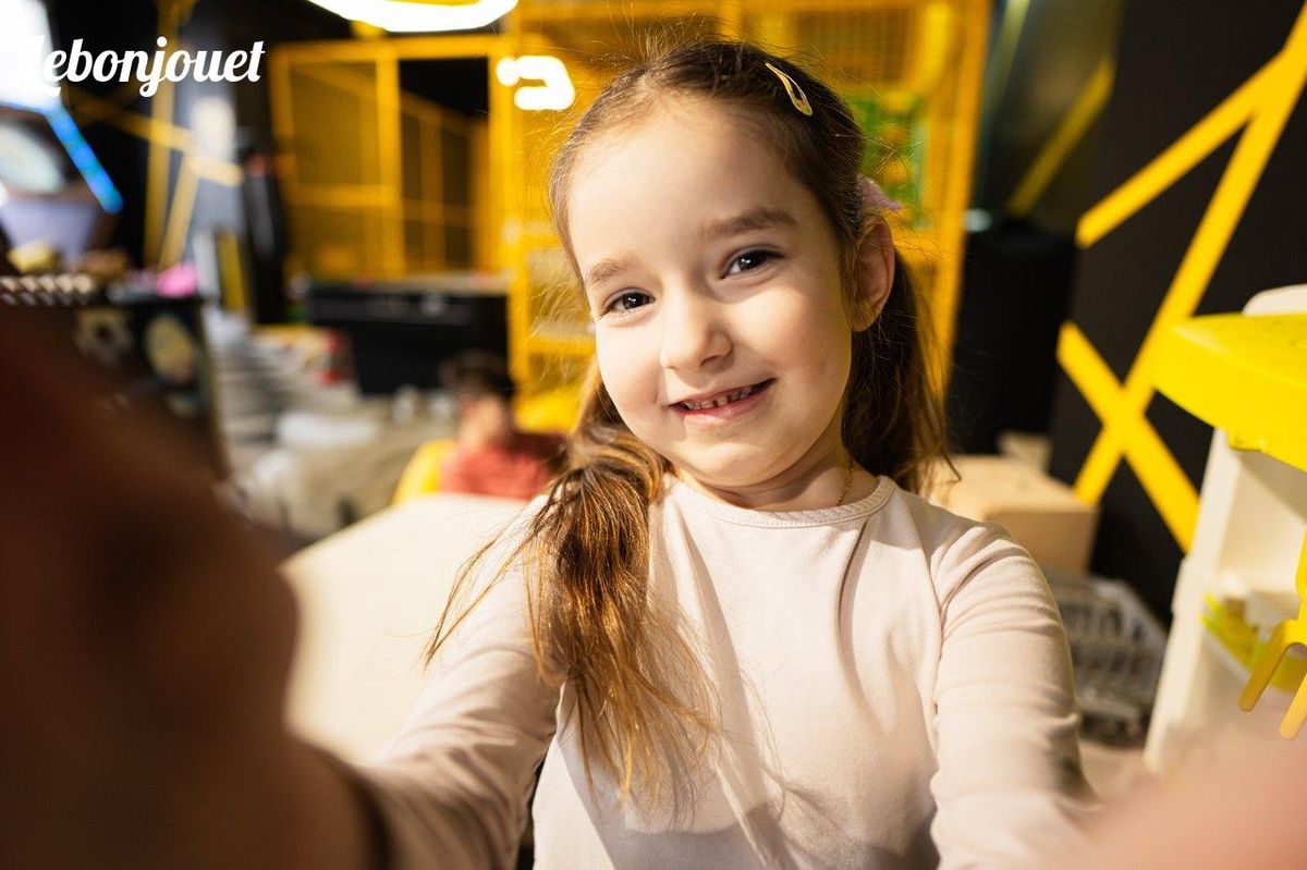 Enfant souriante en plein jeu interactif, idéale pour une sortie culturelle ludique.