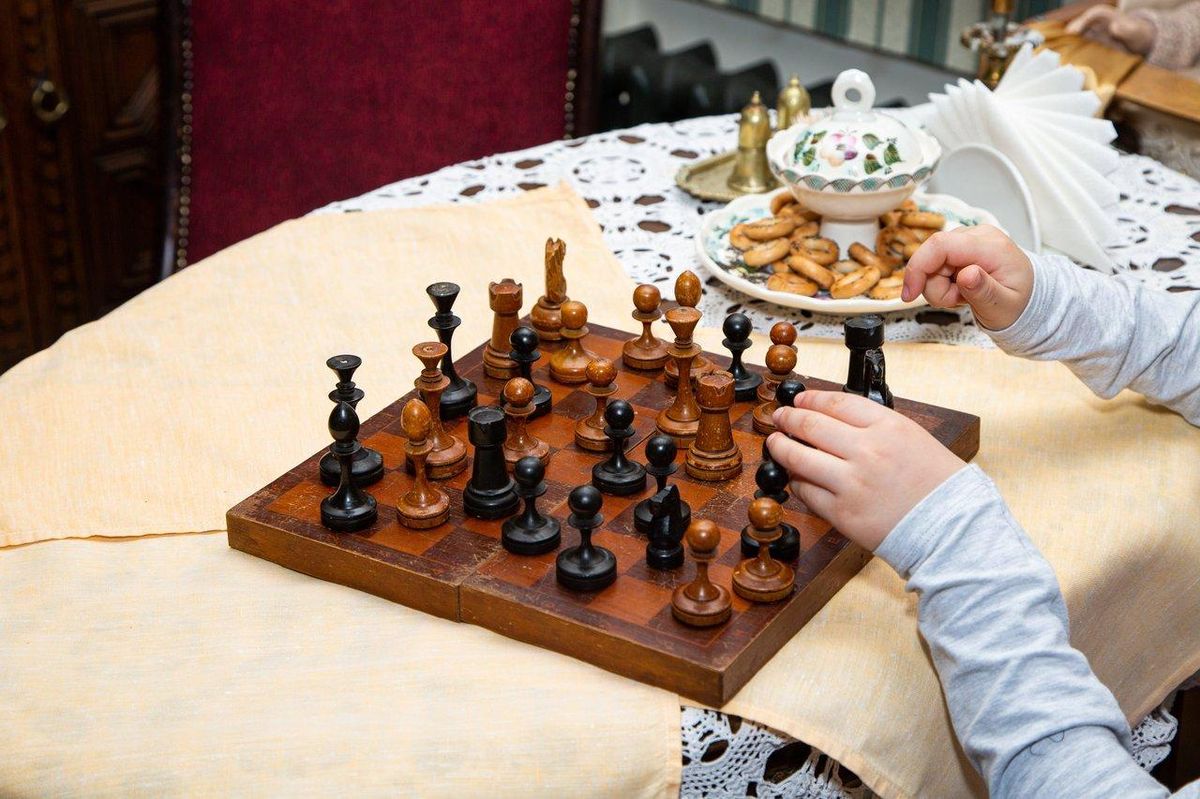 Enfants concentrés jouant aux échecs en bois dans un environnement Montessori, favorisant développement stratégique et calme.