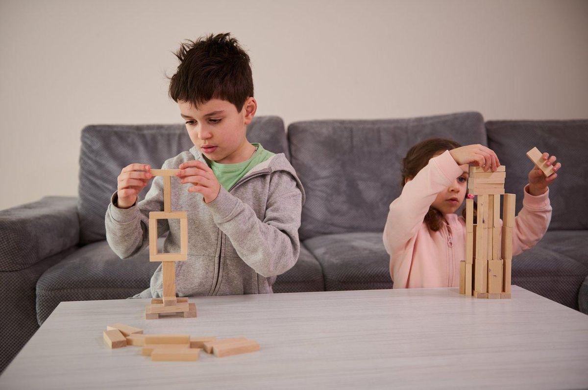 Enfants construisant une structure complexe avec des blocs en bois dans un cadre familial, stimulant leur créativité.