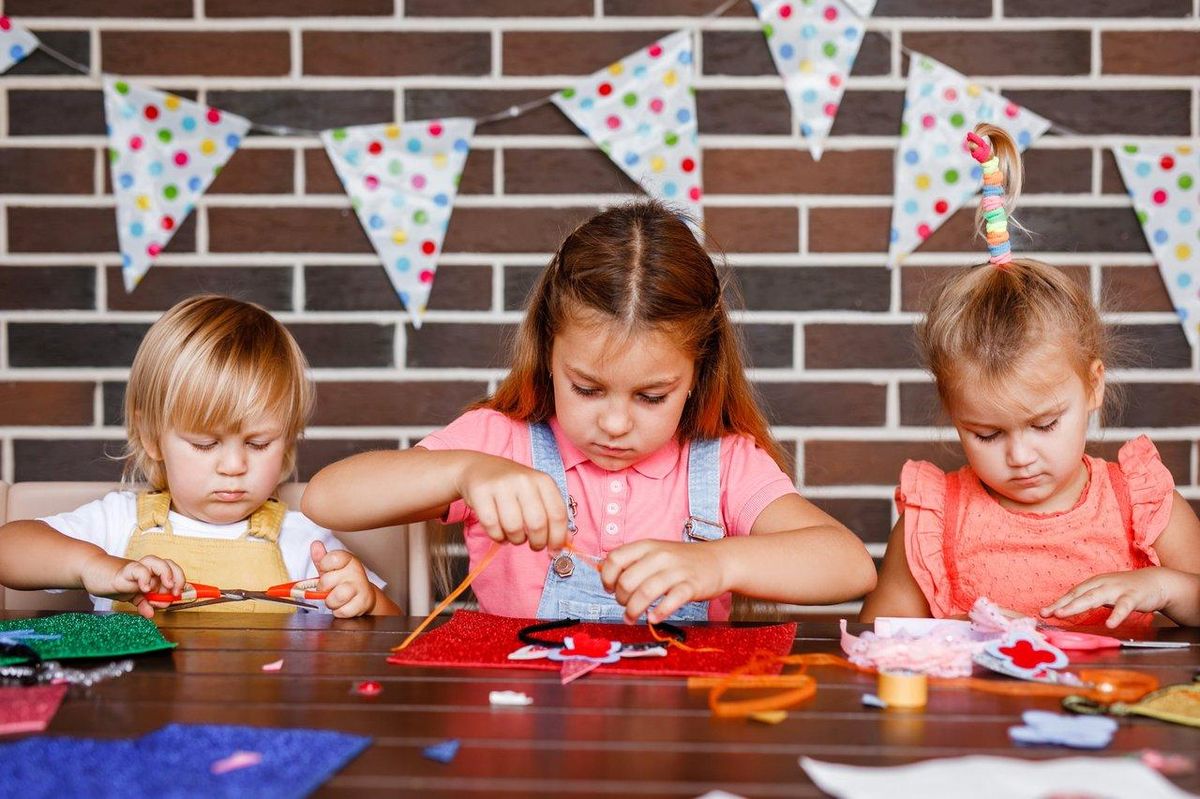 Enfants créant des masques de super-héros lors d’un atelier créatif convivial pendant les vacances.
