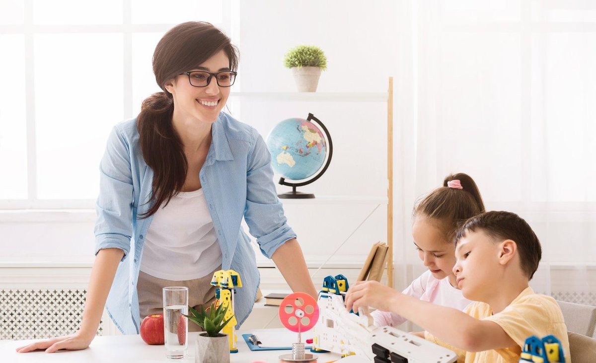 Enfants jouant à un jeu de société en cercle dans une classe, favorisant le développement des compétences sociales.