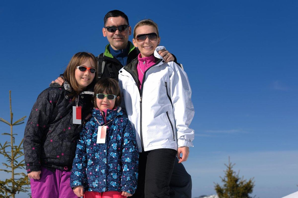 Famille en montagne avec matériel de ski, illustrant le coût d’un family mountain ski trip selon la région en hiver.