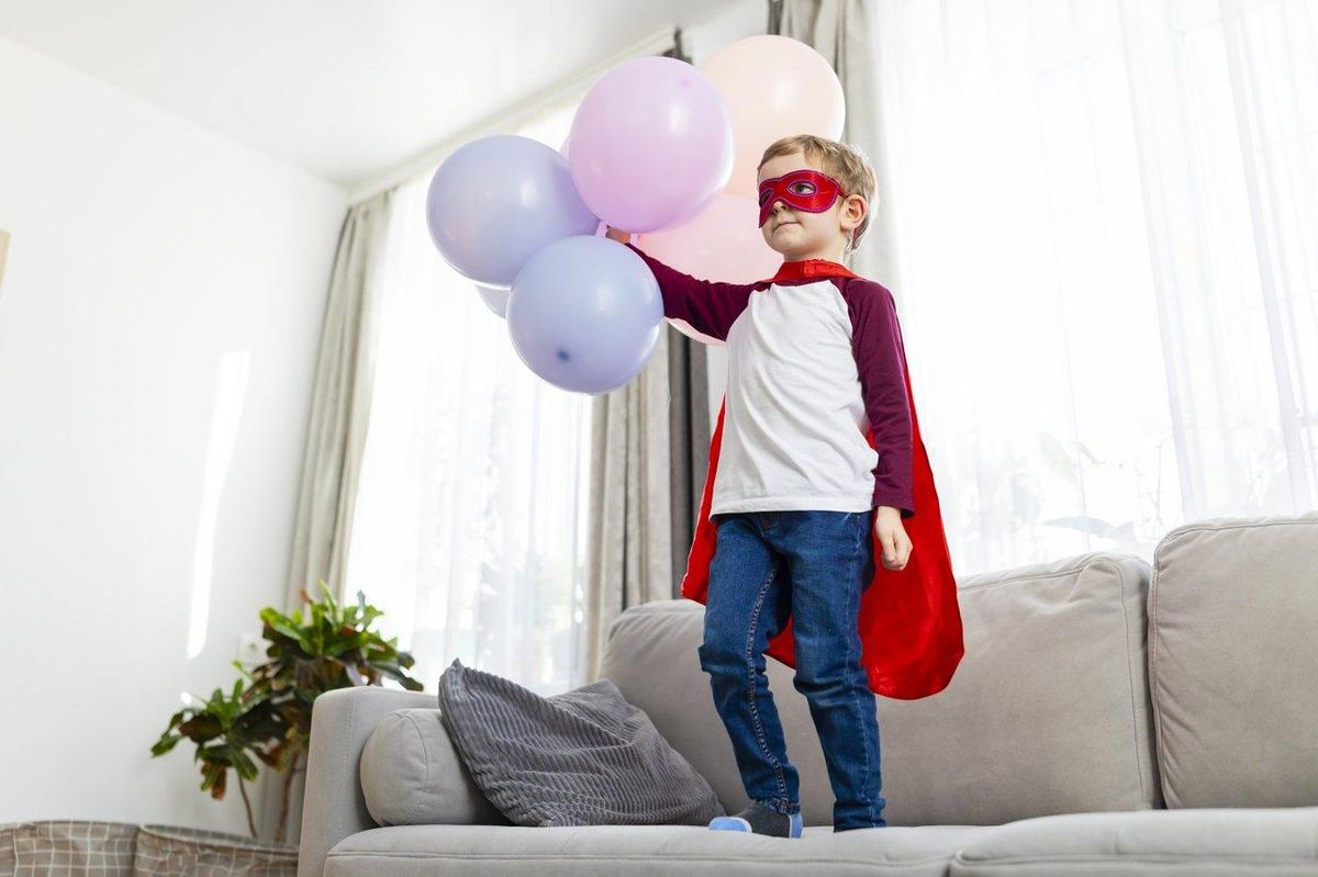 Jeune garçon en costume de super-héros avec ballons, illustrant l'attrait des costumes colorés et jouets Avengers.