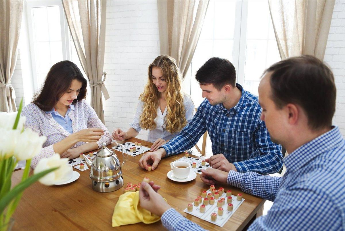 Joueurs de jeux de société s'amusant autour d'une table scolaire lors d'une partie conviviale.