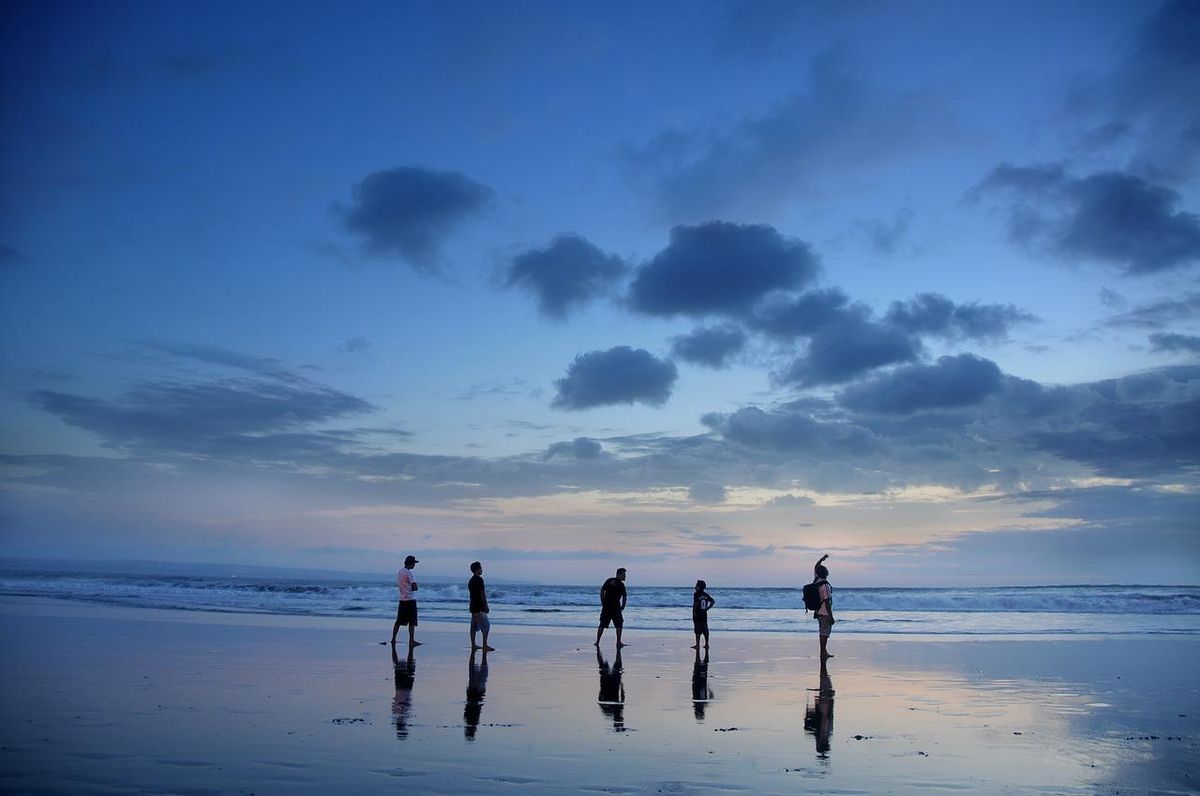 Marche en famille sur la plage au crépuscule, un moment de proximité partagée.