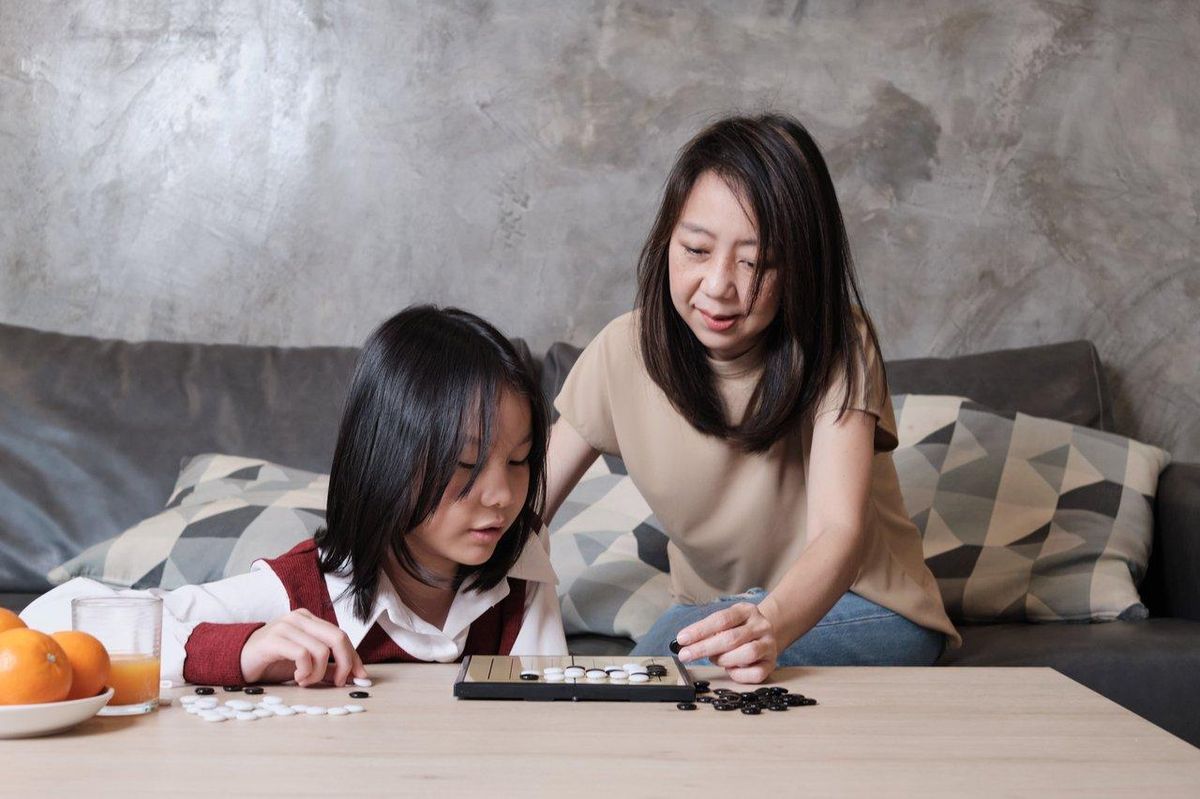 Parent et enfant profitent d’un moment ludique autour d’un jeu de société, renforçant leur complicité.
