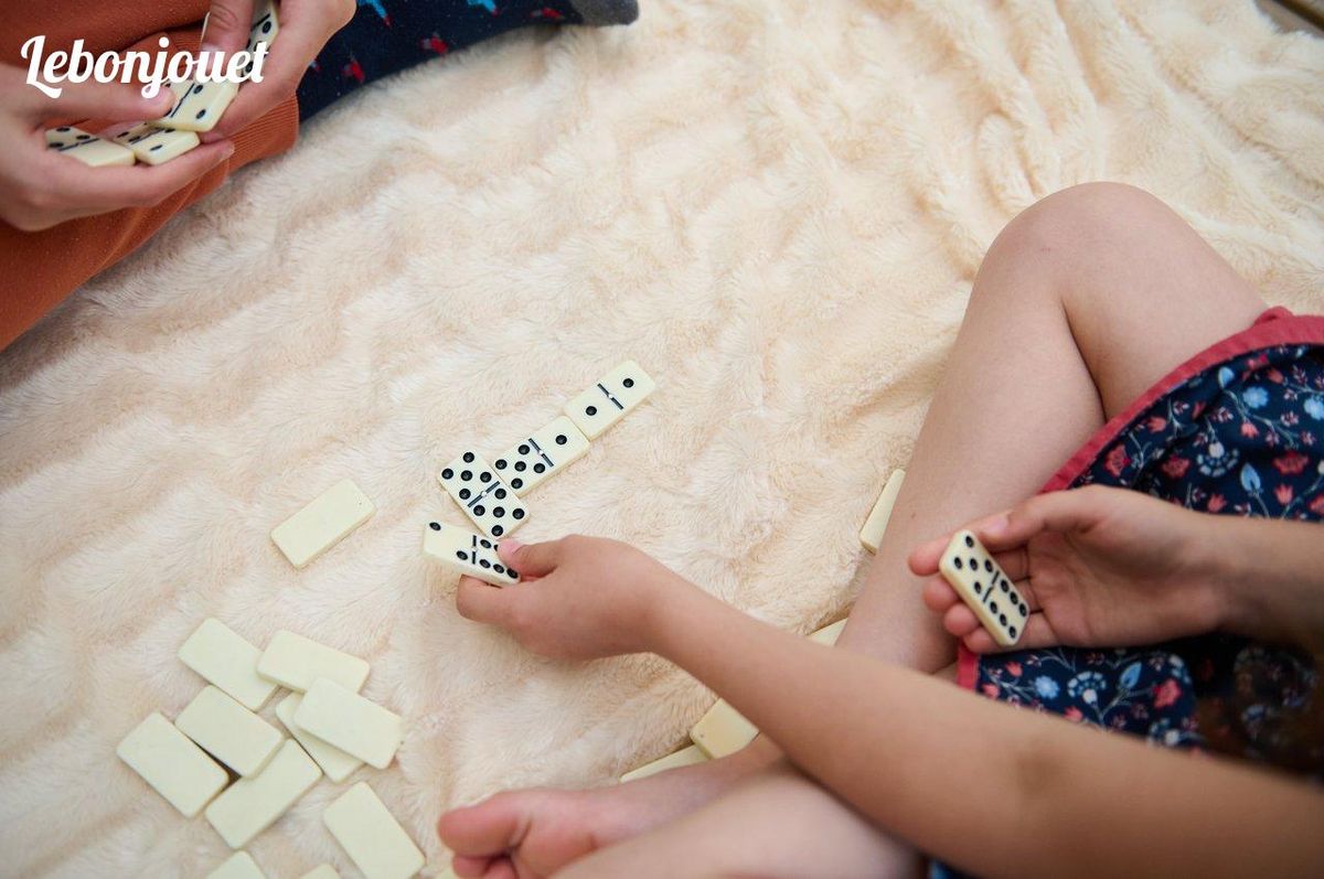 Partie de dominos: stimuler l'esprit selon l'âge aide au développement des enfants.