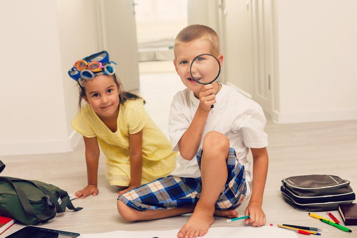 Plateau coloré de children detective boardgame avec enfants jouant à Cluedo Junior, pions et carnet de détective.