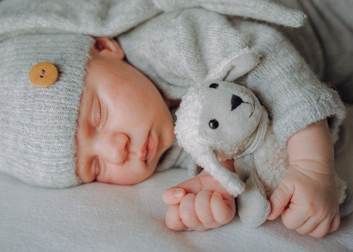 Un bébé câlinant son doudou dans une ambiance douce et chaleureuse, favorisant un sommeil paisible.
