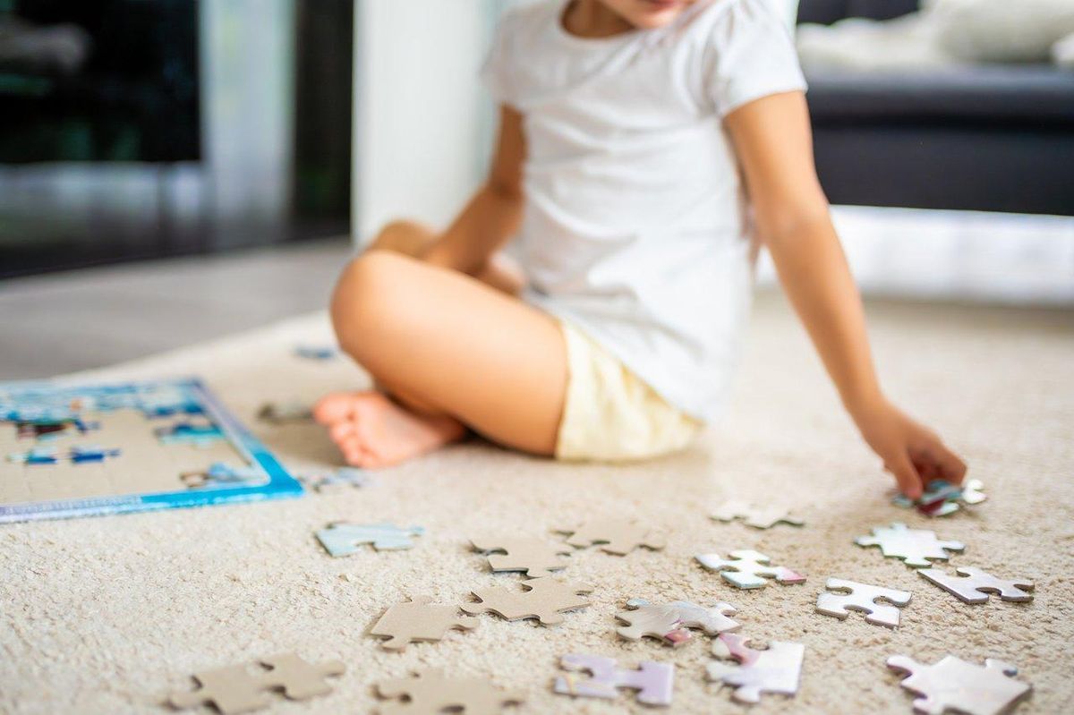 Un enfant assemble un puzzle Disney coloré, stimulant sa concentration et son développement cognitif.