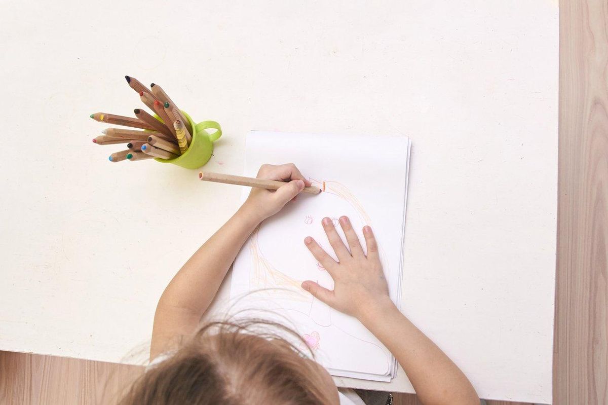 Un enfant coloriant un dessin d'Iron Man avec des crayons de couleur, favorisant la créativité chez les jeunes fans d'Avengers.