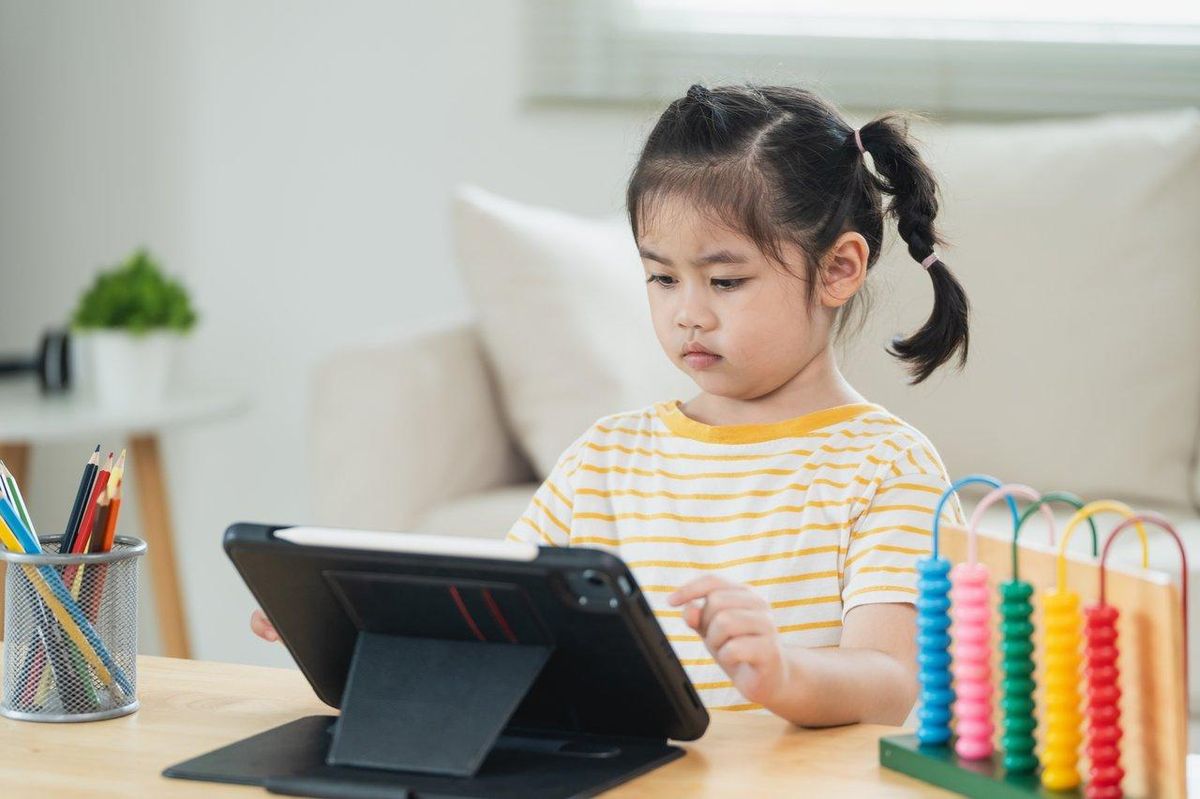 Un enfant joue à un jeu voxel sur tablette dans un univers coloré, illustrant l'engouement pour Hytale chez les jeunes.