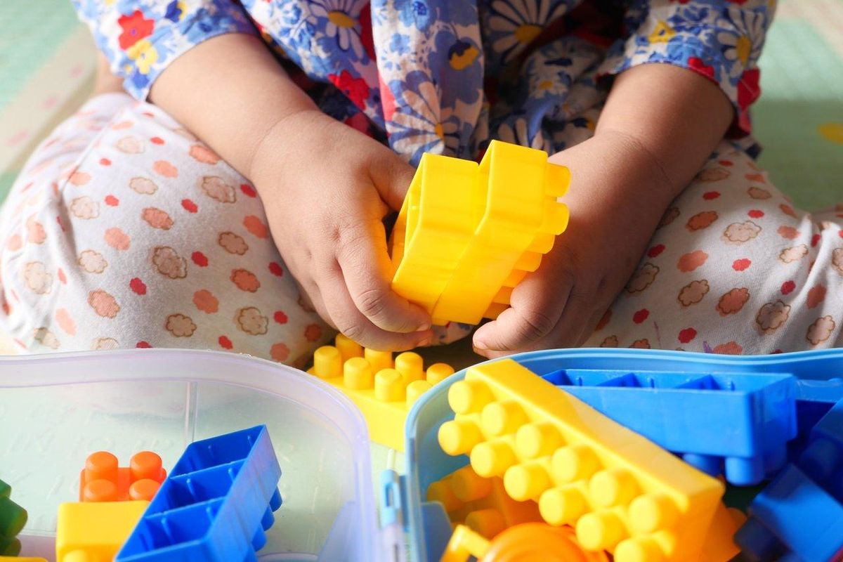 Un enfant joue avec des blocs de construction adaptés à son âge, stimulant créativité et concentration dans un environnement sécurisé.