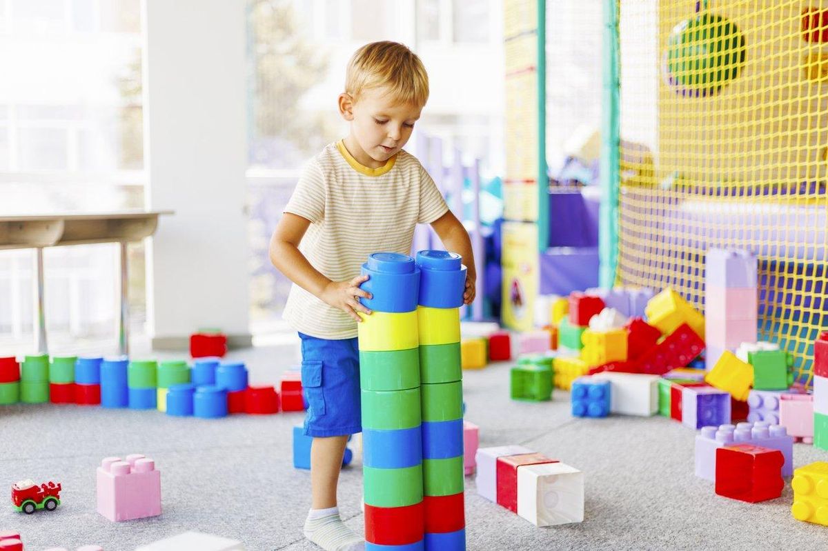 Un enfant joue dans une salle de jeux colorée avec des blocs de construction, stimulant son développement.