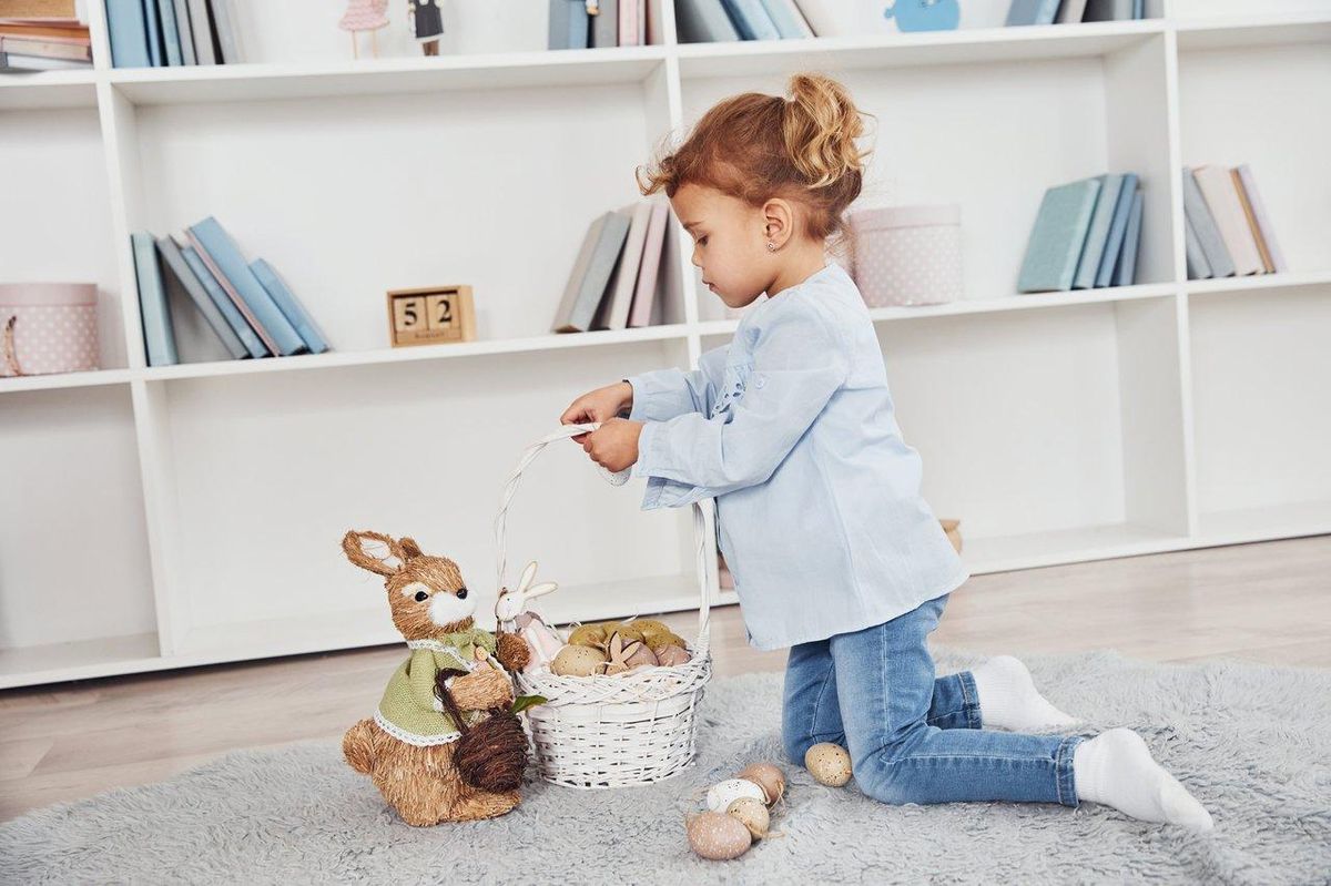 Un enfant range soigneusement son doudou dans un panier coloré pour éviter sa perte et limiter les crises.