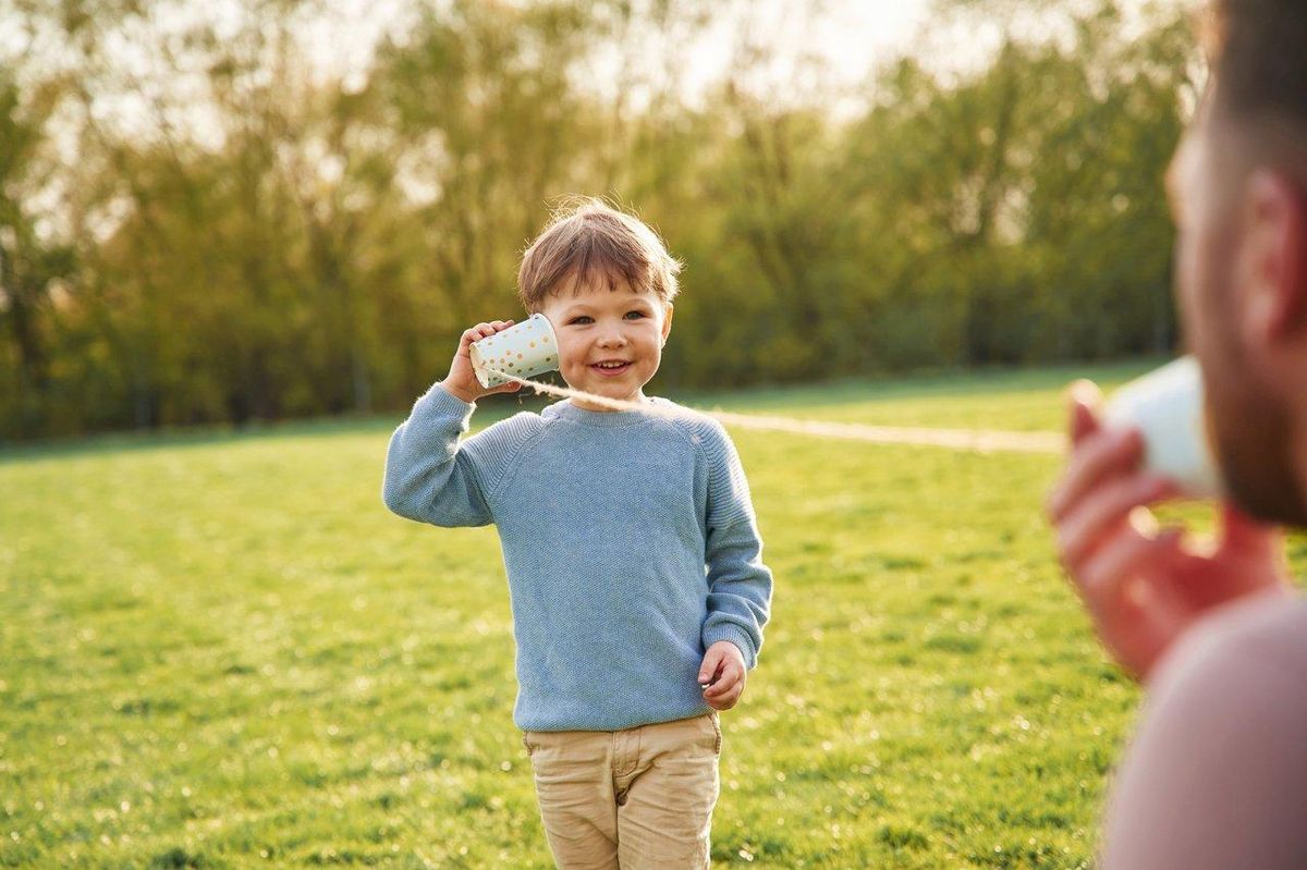 Un enfant utilisant un walkie talkie robuste en extérieur dans un parc lors d'une journée ensoleillée.
