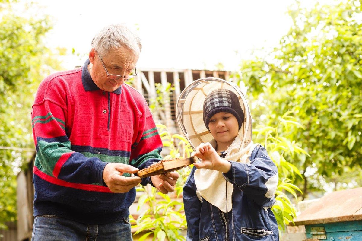 Une famille en tenue d’apiculteur lors d’une activité découverte en nature pour sensibiliser à l'apiculture et à la sécurité des enfants.