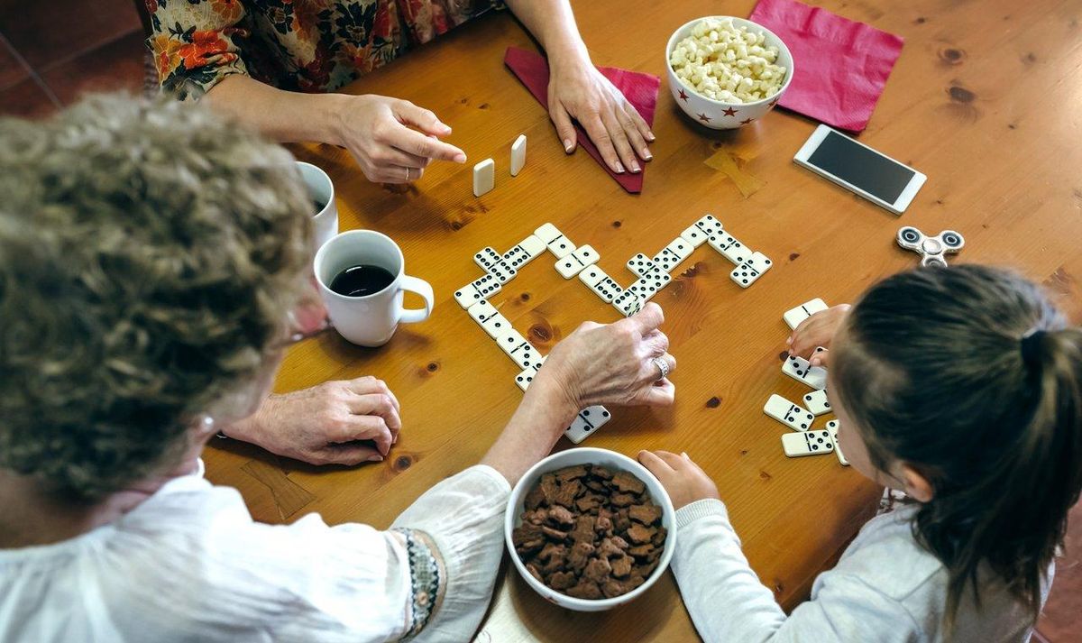 Une famille heureuse joue à un family bilingual board game, alliant divertissement et apprentissage linguistique.