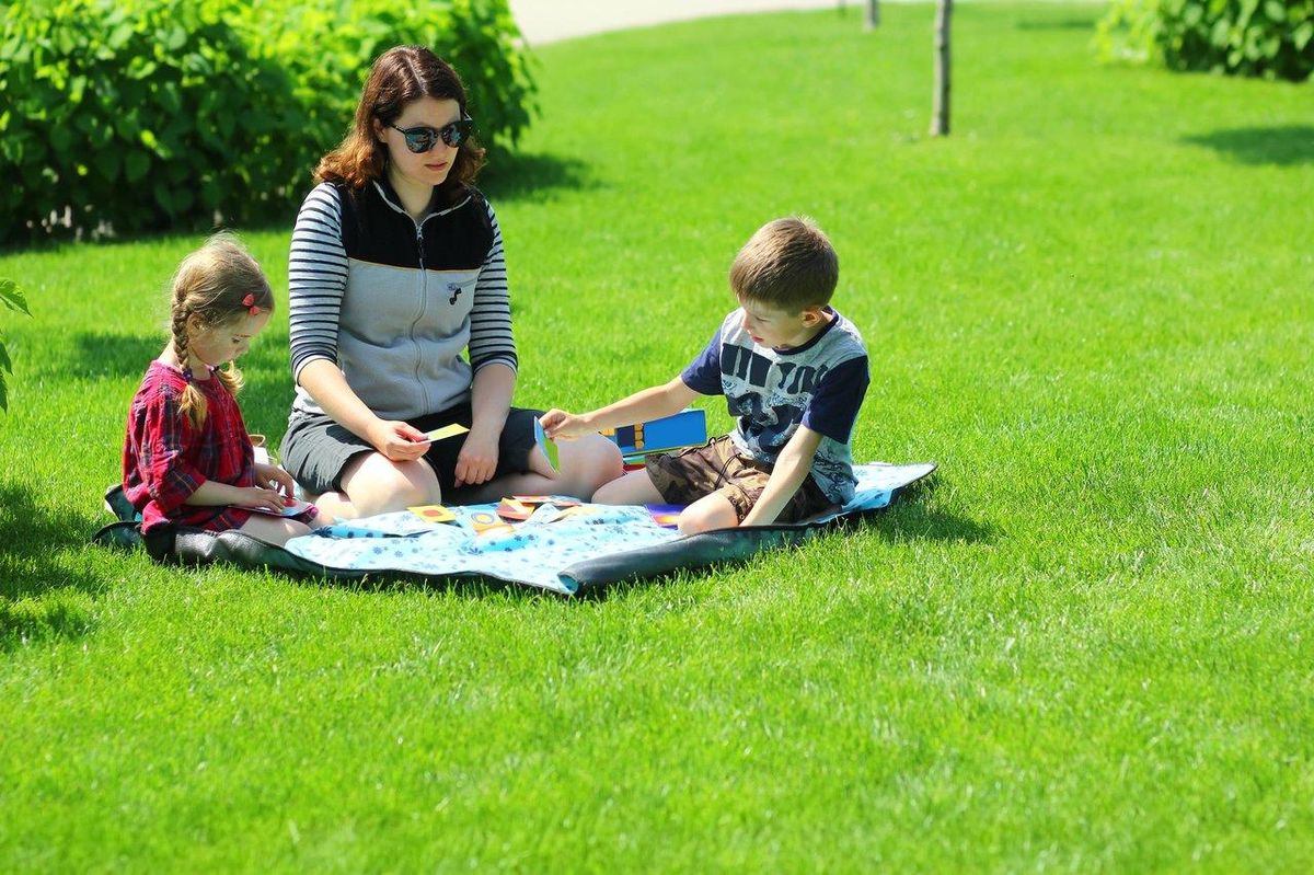 Une famille profitant de jeux de société en plein air lors d’un pique-nique d’été, parfait pour s’amuser ensemble.