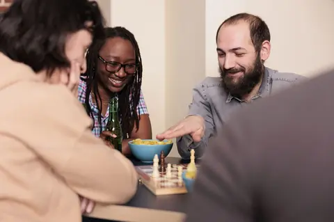 Amis multiethniques jouant aux échecs, un jeu de société stratégique et convivial en famille ou entre amis.