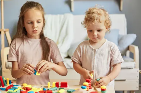 Deux petites filles jouent avec des jouets Montessori éducatifs à la maison pour développer créativité et apprentissage.