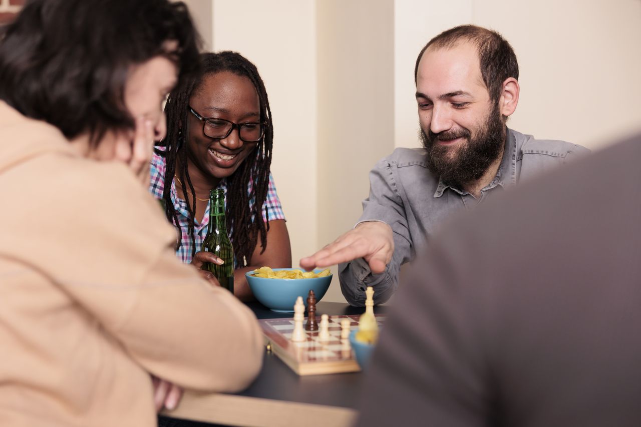 Amis multiethniques jouant aux échecs, un jeu de société stratégique et convivial en famille ou entre amis.