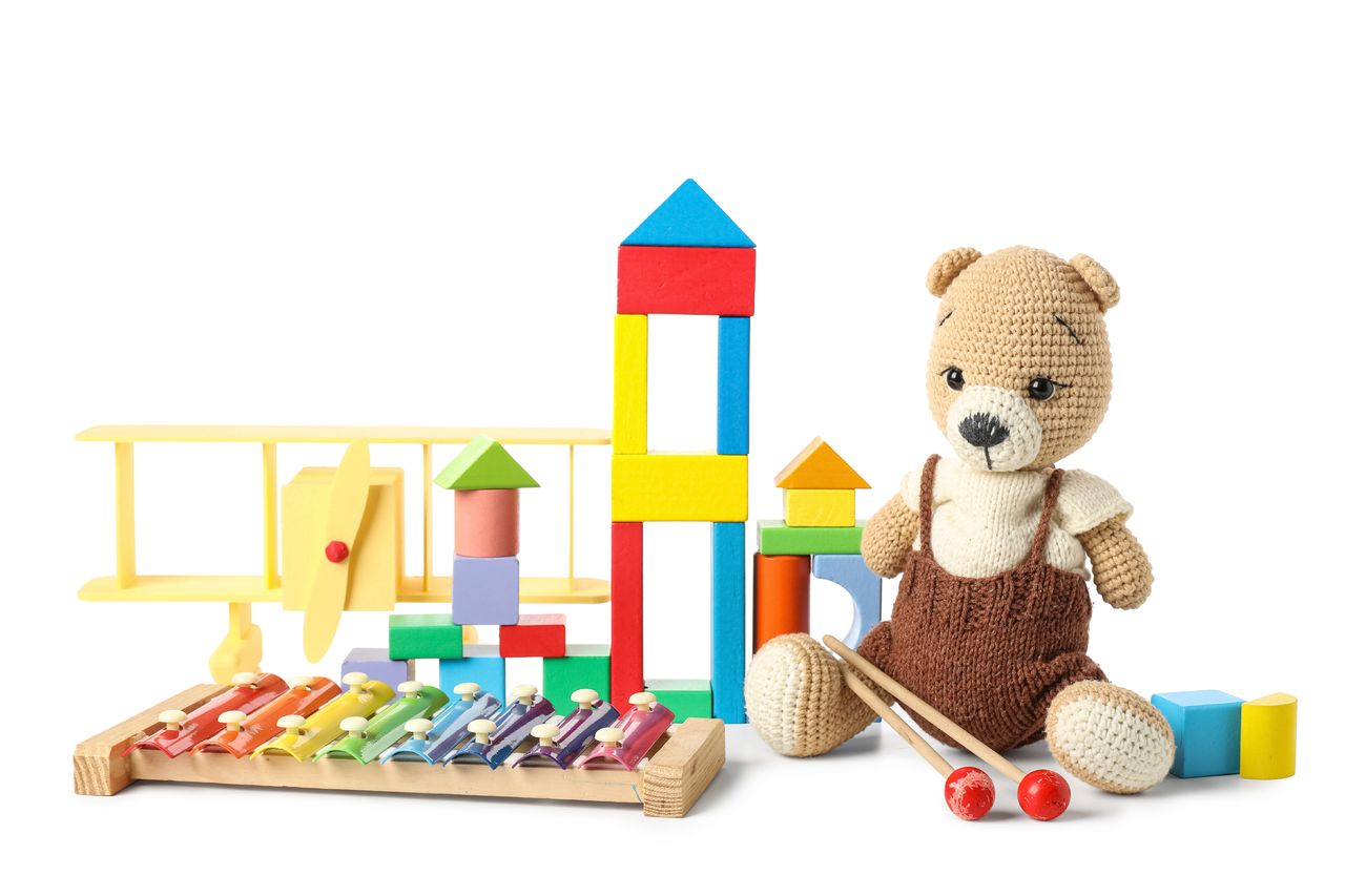 Jouets en bois colorés, xylophone et ours crocheté sur fond blanc.