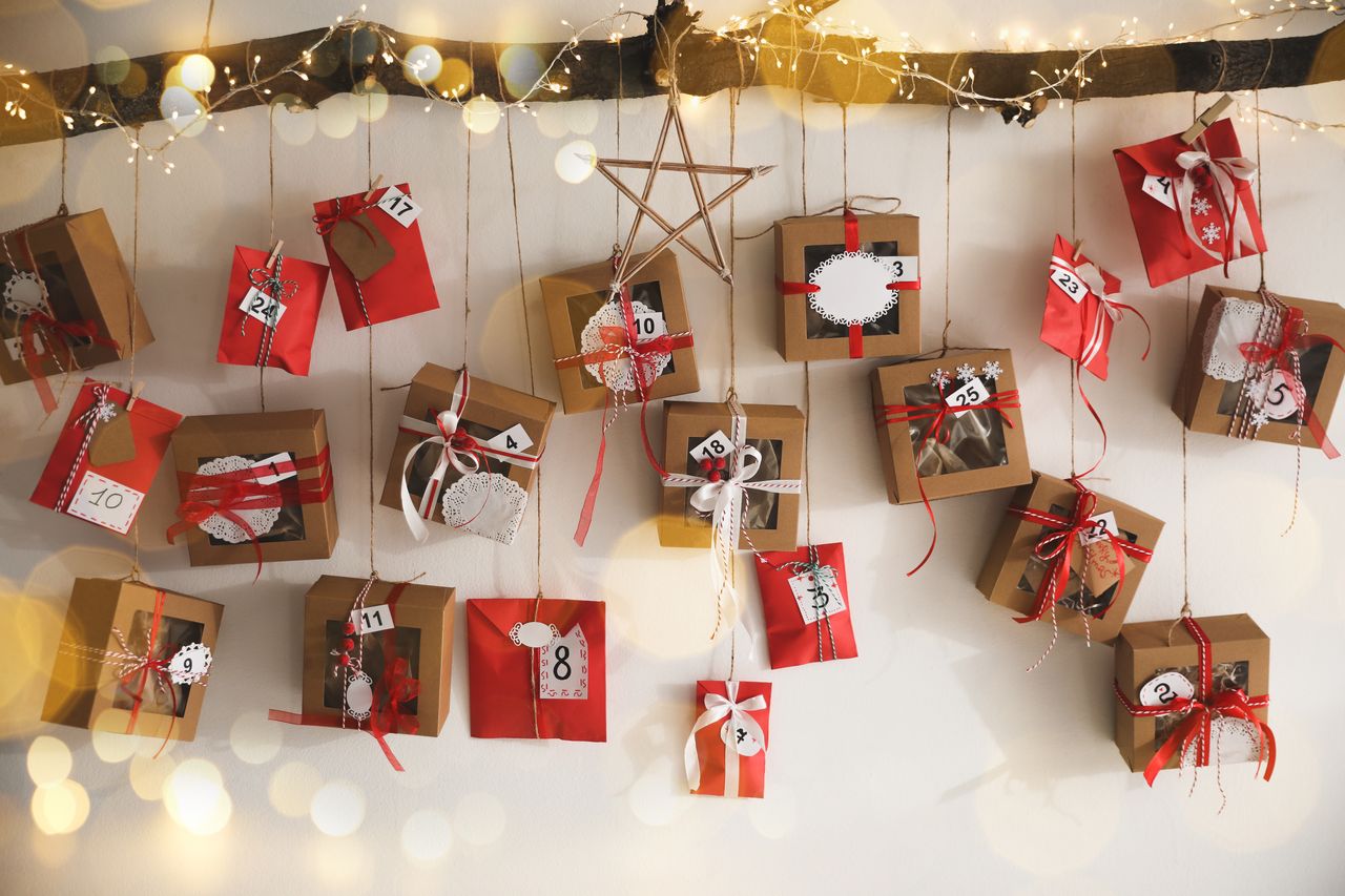 Calendriers de l'Avent 2026 variés avec jouets, créations DIY et coffrets cadeaux festifs suspendus au mur blanc.