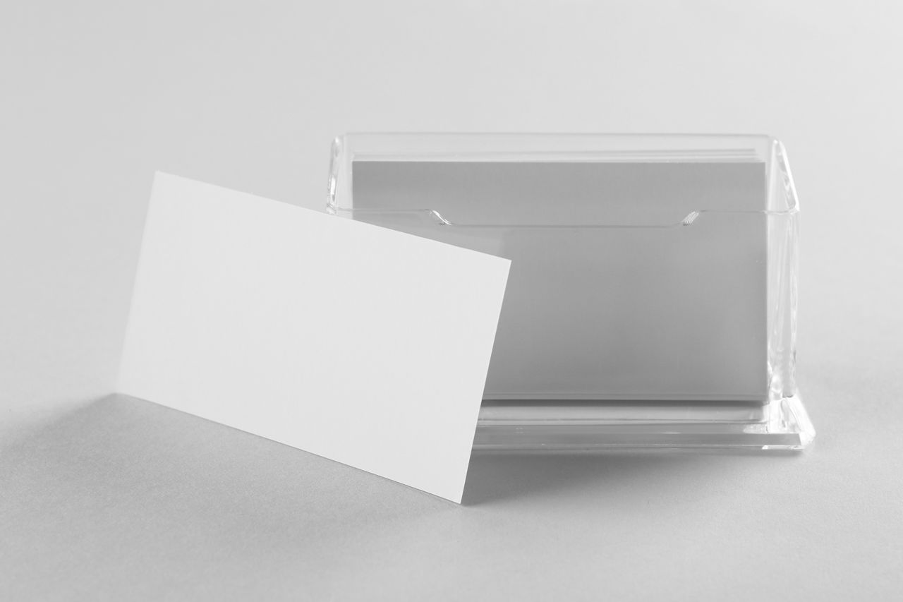 Cartes à collectionner rangées dans une boîte de protection, sur fond lumineux et épuré.