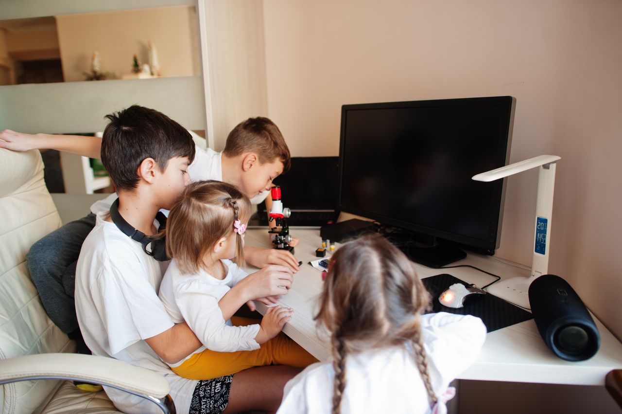 Des enfants apprennent la science avec un microscope à l'intérieur, pendant une journée de forte chaleur.