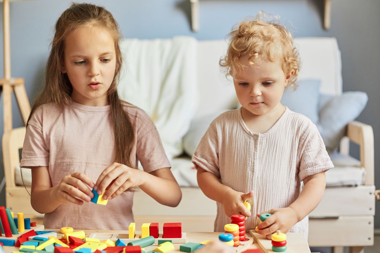 Deux petites filles jouent avec des jouets Montessori éducatifs à la maison pour développer créativité et apprentissage.