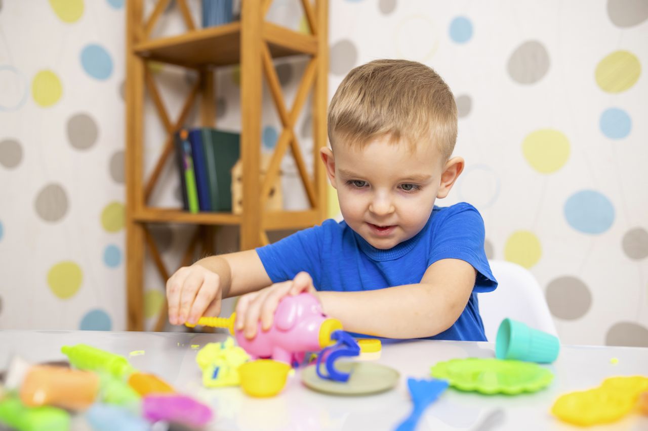 Enfant de 5 ans jouant à la maison avec pâte à modeler, pailles et pinces créatives.