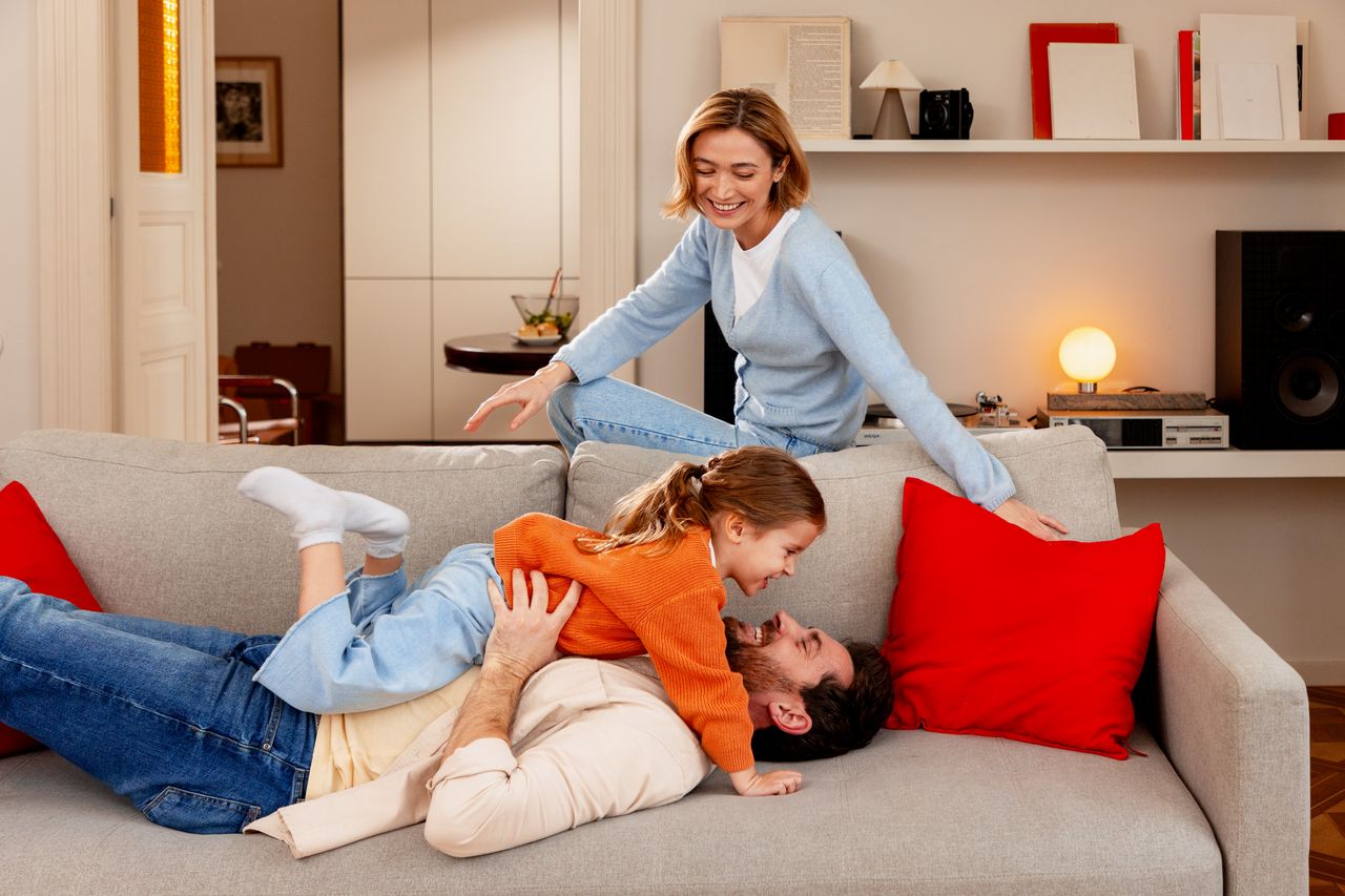 Enfant jouant à un jeu vidéo coloré en famille, moment de bonheur à la maison