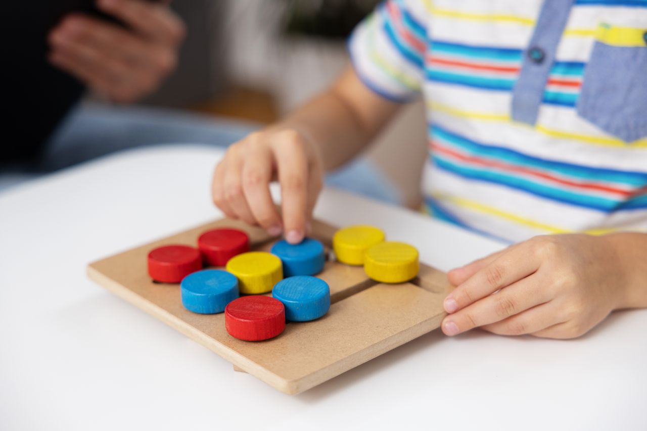 Enfant jouant avec un puzzle éducatif en bois coloré pour développer motricité et cognition.