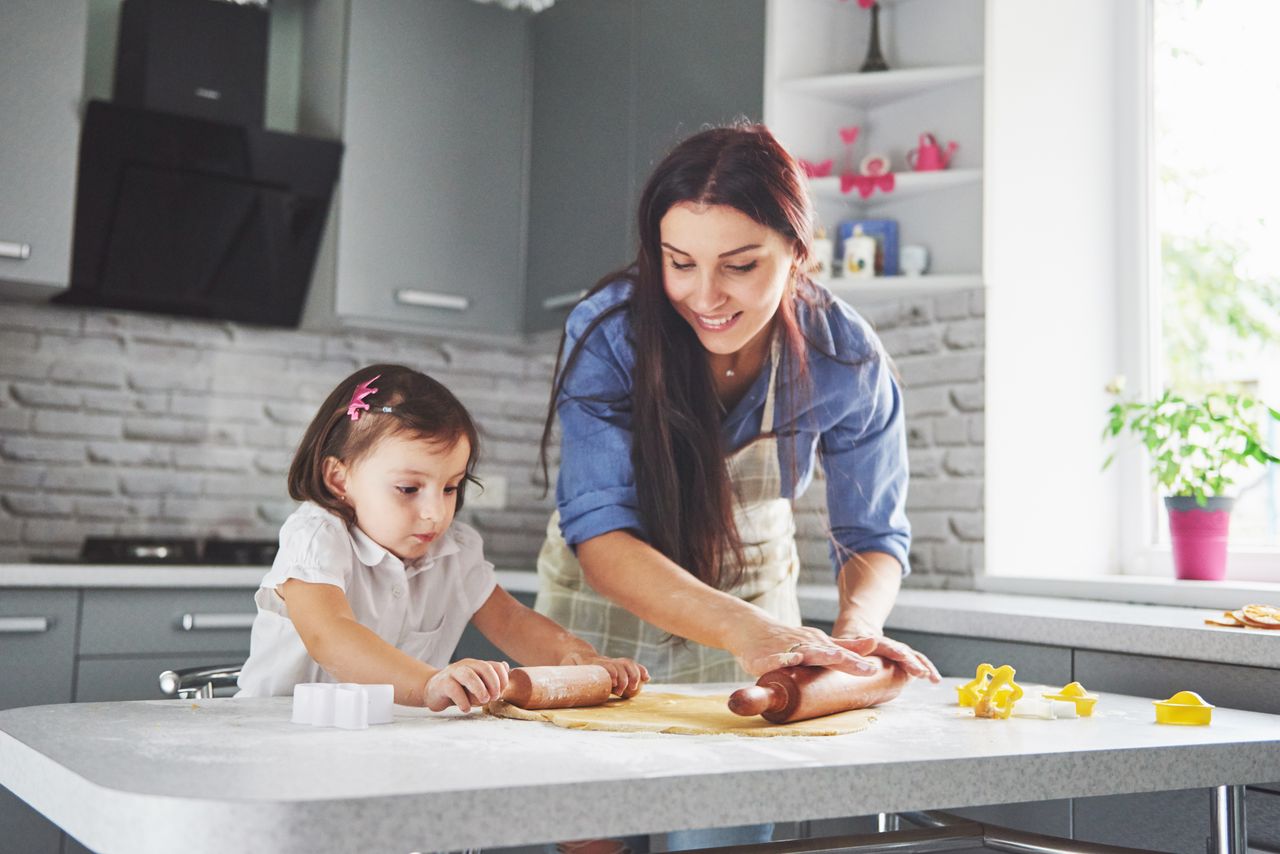 Famille heureuse en cuisine : mère et fille préparent une pâte pour des biscuits maison ensemble.