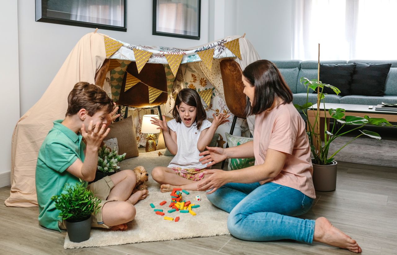 Famille heureuse jouant à un jeu de tour en bois, rires et moments conviviaux partagés.