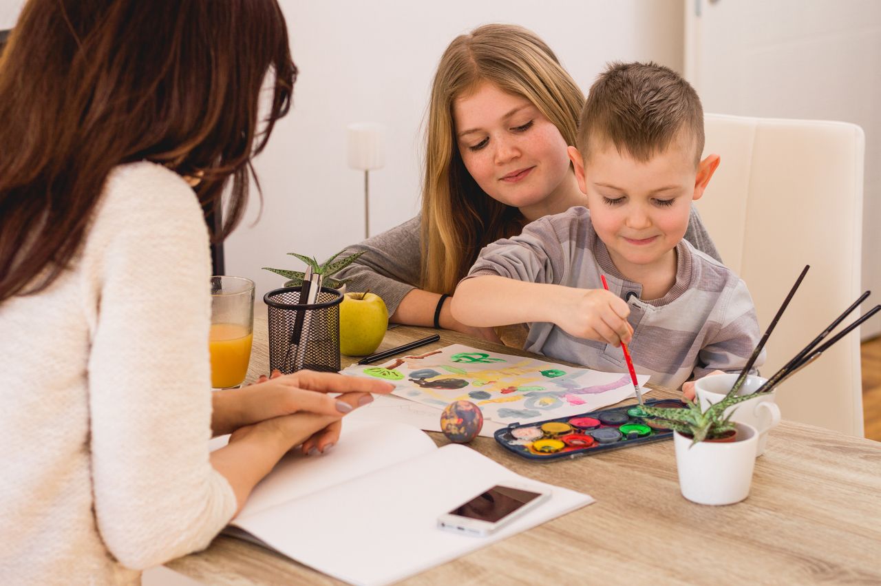 Famille heureuse réunie autour d’un quiz Pokémon estival, cartes, crayons et ambiance ludique à la maison