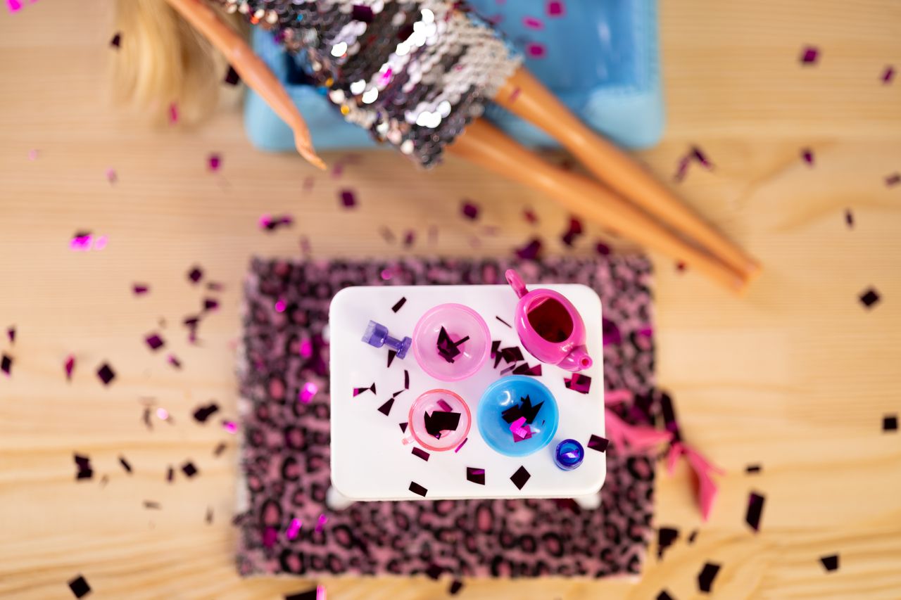 Furby sur une table avec piles, petit tournevis et chiffon de nettoyage pour entretien.