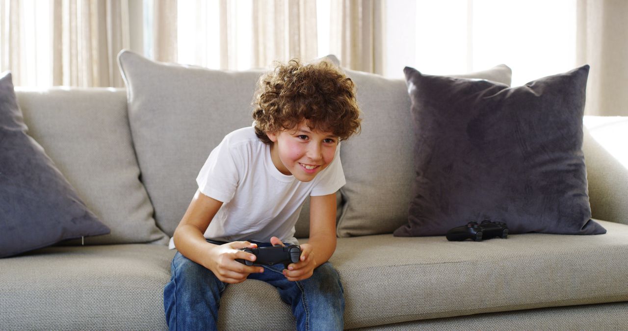 Garçon souriant jouant à la console à la maison, dans l’univers jeunesse Yo-Kai Watch.
