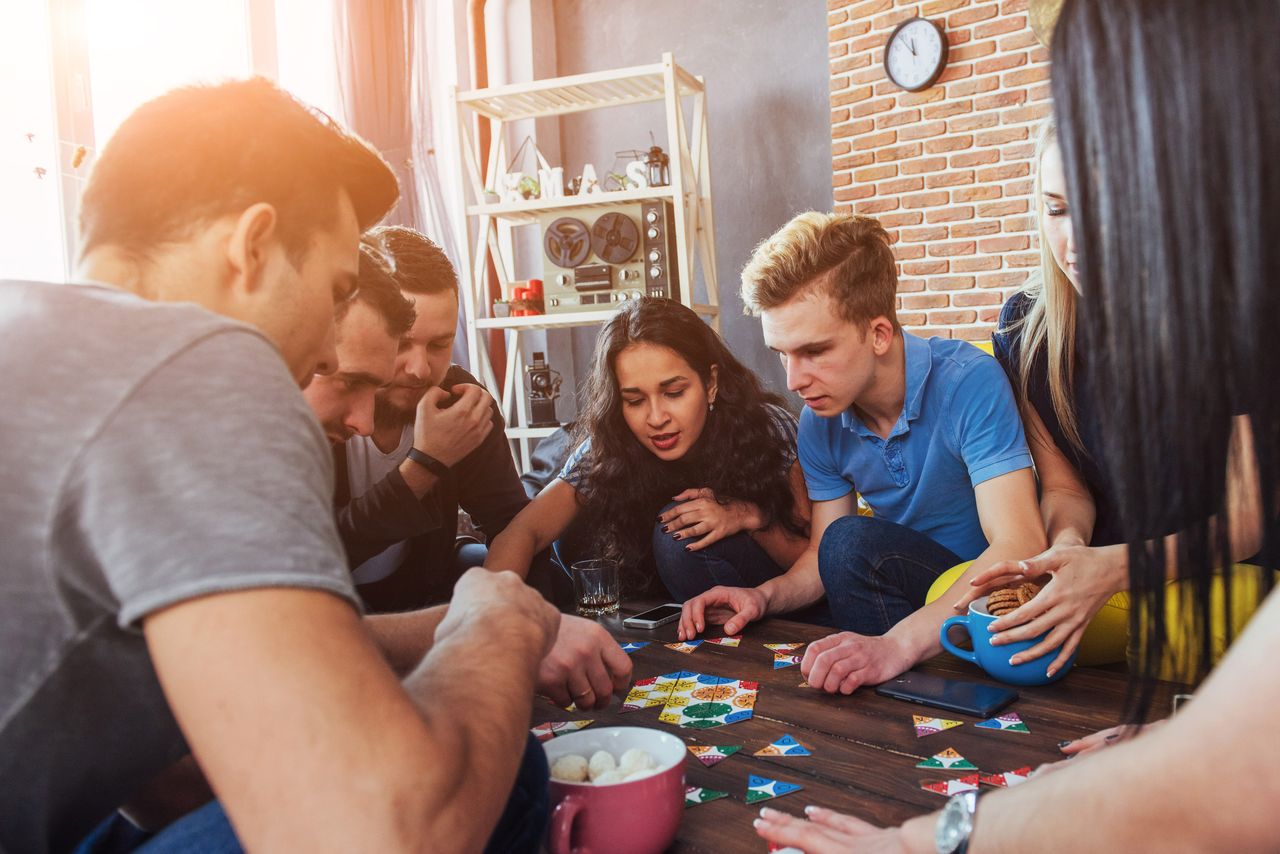 Groupe d’amis jouant à un jeu de société convivial pour une soirée fun et animée
